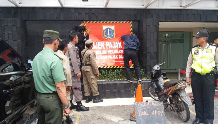 Petugas tengah memasang stiker tunggakan pajak PBB P2 di sebuah hotel di Tamansari. (Tarta)